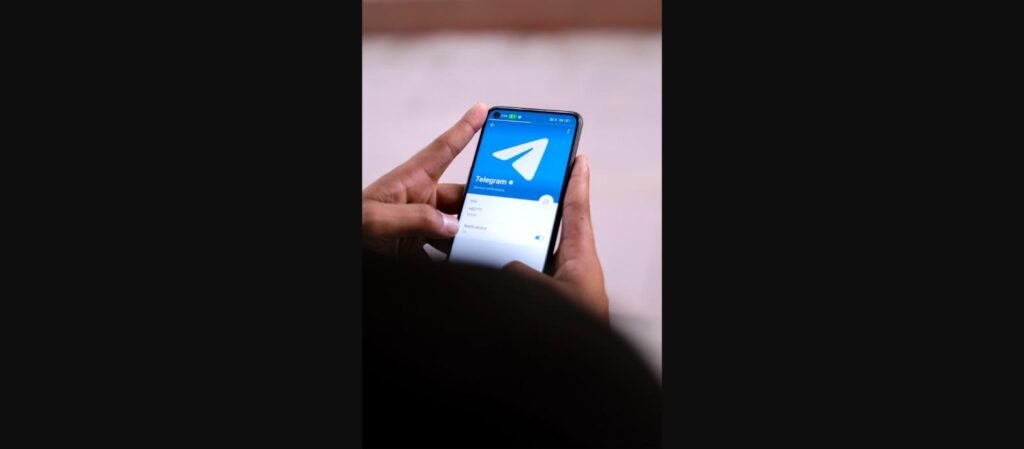 يد تحمل هاتفًا ذكيًا مفتوحًا على تطبيق تيليجرام، توضيح روابط t.me